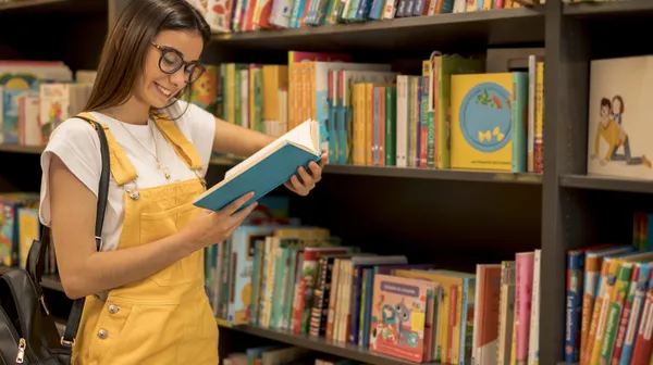 1768482076-teenage-student-reading-book-leaning-shelf (1)